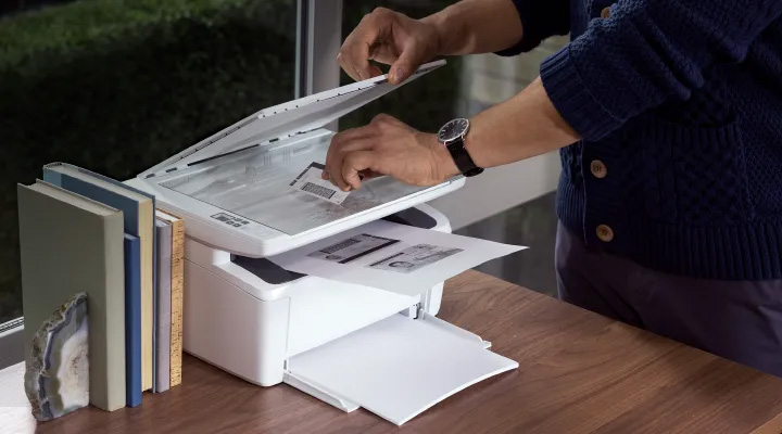 Hombre escaneando documento en el cristal de la multifuncional HP LaserJet M141W.