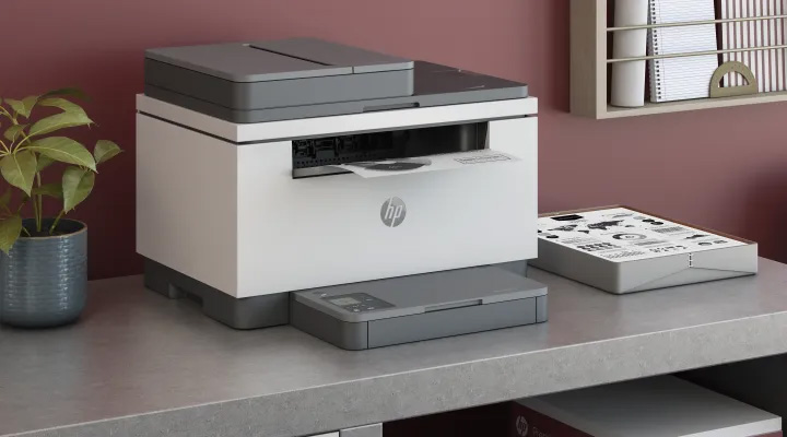 Impresora láser multifunción HP M236sdw blanca en uso sobre un escritorio moderno, perfecta para tu casa