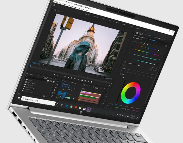 Primer plano de la pantalla de una laptop HP ProBook 445 G11 abierta. Muestra una aplicación de edición de video con la línea de tiempo y controles de color. En el monitor se ve un clip de una persona con cabello turquesa en una calle urbana.