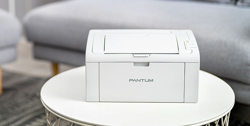 Impresora Monocromática Láser Pantum P2509W sobre una mesa redonda.