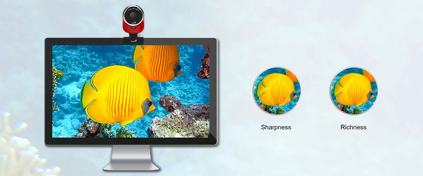 Webcam Genius QCam 6000 instalada encima de un monitor de escritorio mostrando dos peces mariposa amarillos en un arrecife, y a la derecha dos círculos comparando la nitidez (Sharpness) y la riqueza de color (Richness) de la imagen