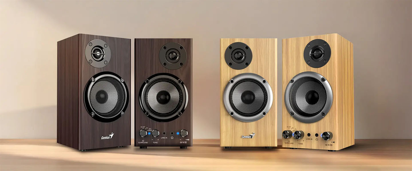 Cuatro parlantes Genius en exhibición sobre una superficie de madera, dos con terminación en madera oscura y dos en madera clara, mostrando sus diseños frontales y controles integrados