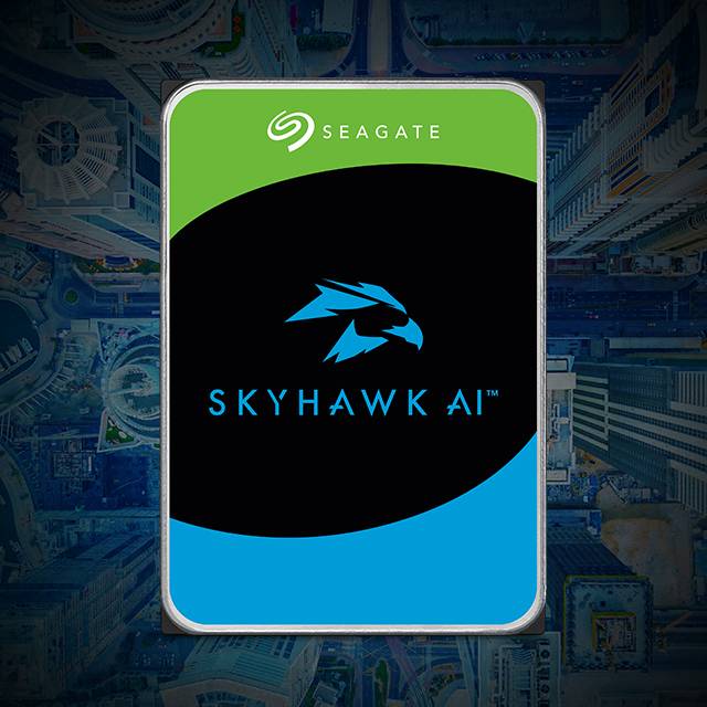 La imagen muestra un disco duro de la marca Seagate, modelo SkyHawk AI, con un diseño de fondo que parece una vista aérea de una ciudad. El disco duro tiene una etiqueta con los colores verde, negro y azul, y el logo de un halcón en el centro. La palabra SEAGATE está en la parte superior de la etiqueta, y SKYHAWK AI está en la parte inferior.