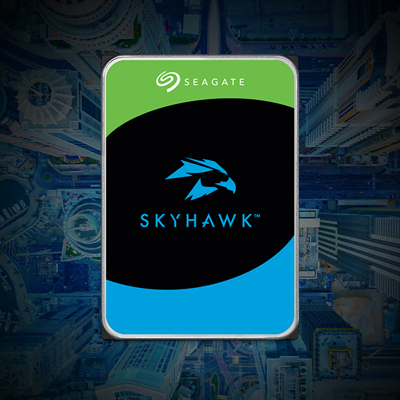 La imagen muestra un disco duro de la marca Seagate, modelo SkyHawk, con un diseño de fondo que parece una vista aérea de una ciudad. El disco duro tiene una etiqueta con los colores verde, negro y azul, y el logo de un halcón en el centro. La palabra SEAGATE está en la parte superior de la etiqueta, y SKYHAWK está en la parte inferior.