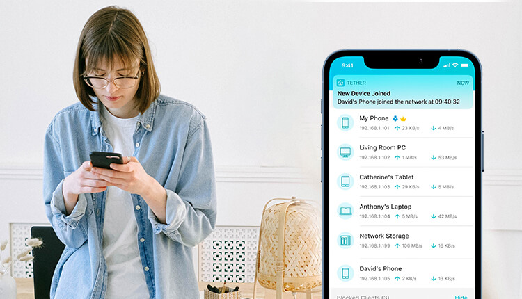 Una mujer joven, con anteojos y una camisa de jean, está mirando y usando un teléfono inteligente negro que sostiene con ambas manos. A la derecha, superpuesta, se ve la pantalla de una aplicación móvil con el título Tether, mostrando una notificación de Nuevo dispositivo conectado y una lista de dispositivos conectados a la red, incluyendo Mi teléfono, PC del living, Tablet de Catherine, Laptop de Anthony y Almacenamiento de red, junto con información sobre sus direcciones IP y velocidades de carga y descarga.