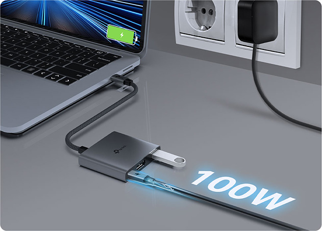Notebook conectada a un Hub USB-C 3 en 1 TP-Link UH3020C con carga rápida de 100W y múltiples puertos, incluyendo un USB y HDMI, enchufado a una toma de corriente.