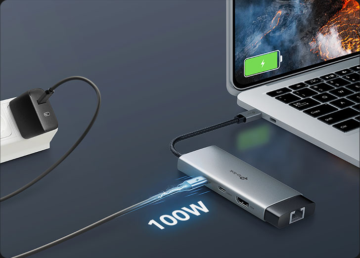 Hub USB-C TP-Link UH6120C plateado con carga de paso de 100W Power Delivery, conectado a una notebook con la batería cargando. El hub está conectado a un cargador de pared que suministra energía. El número 100W está resaltado con un efecto de rayo de energía que entra al hub. El producto está listo para cargar vuestros dispositivos y conectar periféricos simultáneamente.