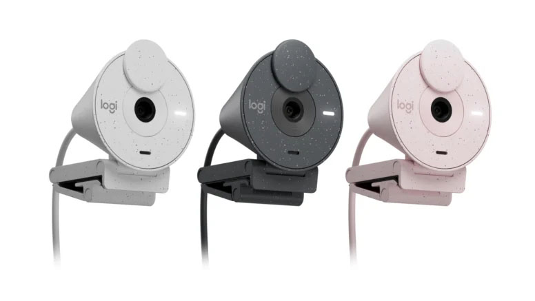 Tres webcams Logitech Brio 300 en fila con sus soportes y cables. Los colores son blanco, grafito y rosa.
