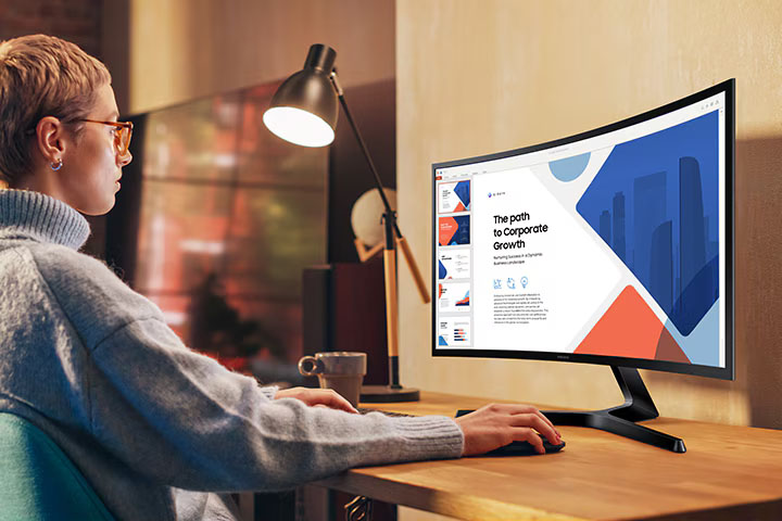 Una mujer está sentada frente a un escritorio utilizando un monitor.