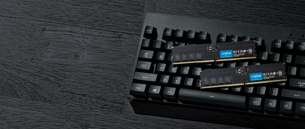 Módulos de memoria RAM Crucial DDR sobre un teclado mecánico negro en un escritorio oscuro