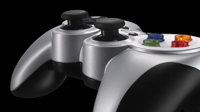 Primer plano de las agarraderas y la parte superior del mando inalámbrico Logitech F710 en color plateado y negro, mostrando los joysticks analógicos y parte de los botones de acción de colores