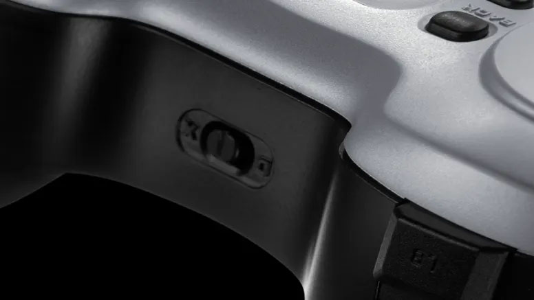 Primer plano del lateral del mando inalámbrico Logitech F710 en color gris oscuro, mostrando el interruptor de modo X/D para compatibilidad con XInput y DirectInput