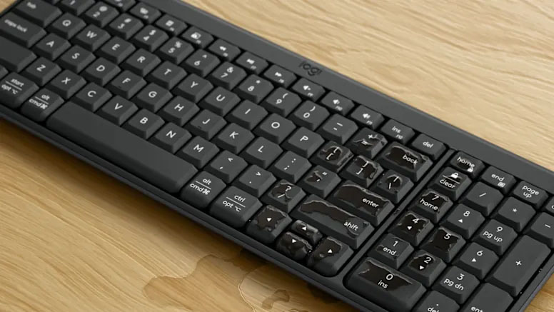 Teclado Compacto Inalámbrico Bluetooth Logitech K250 resistente a derrames, con gotas de agua sobre un escritorio de madera clara
