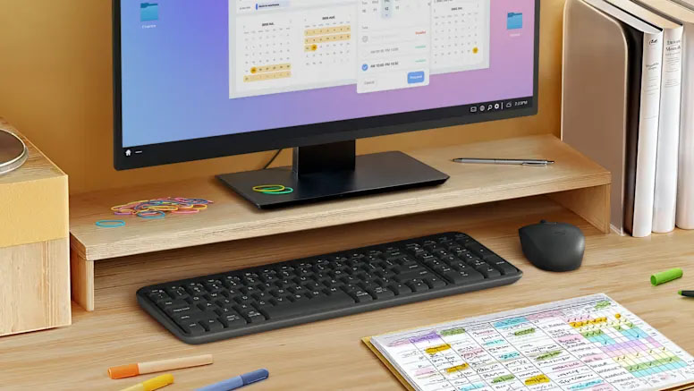 Teclado Compacto Inalámbrico Bluetooth Logitech K250 con mouse sobre escritorio de madera, junto a monitor, calendario, carpetas y útiles escolares
