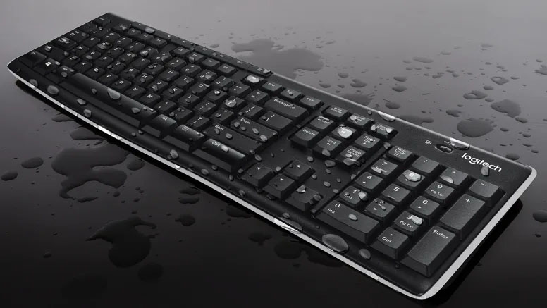 Teclado Inalámbrico Logitech K270 con resistencia a salpicaduras, cubierto de gotas de agua sobre superficie negra