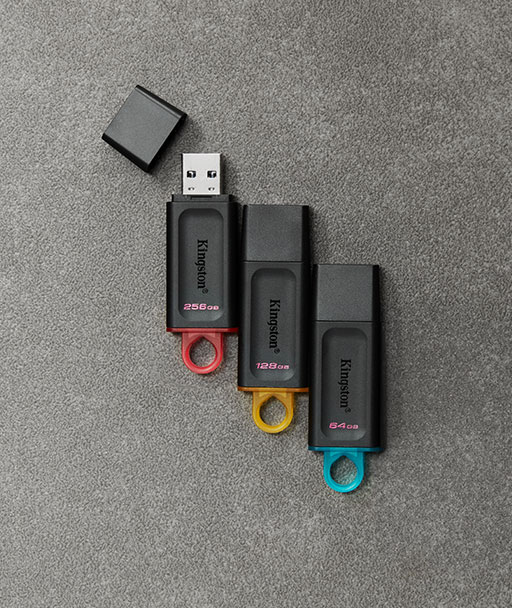 Vista superior de tres unidades flash USB DT Exodia diferentes en varios colores por capacidad en una alfombra gris