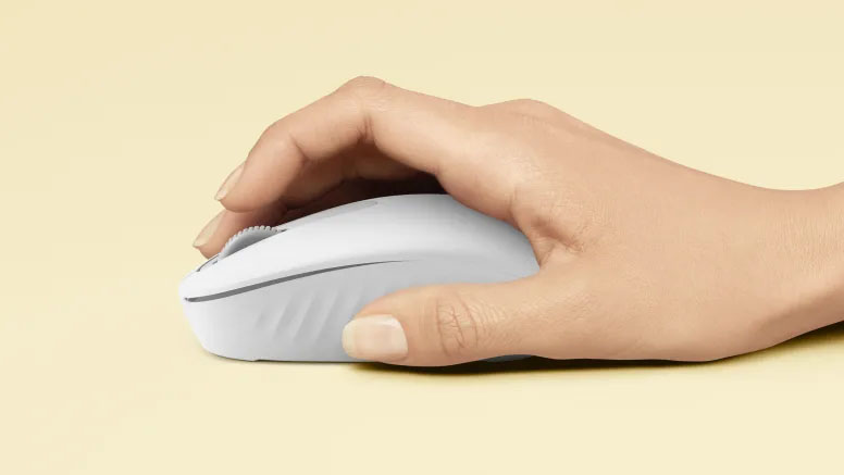 Mano usando el mouse Logitech M196 Bluetooth en color blanco sobre fondo beige claro