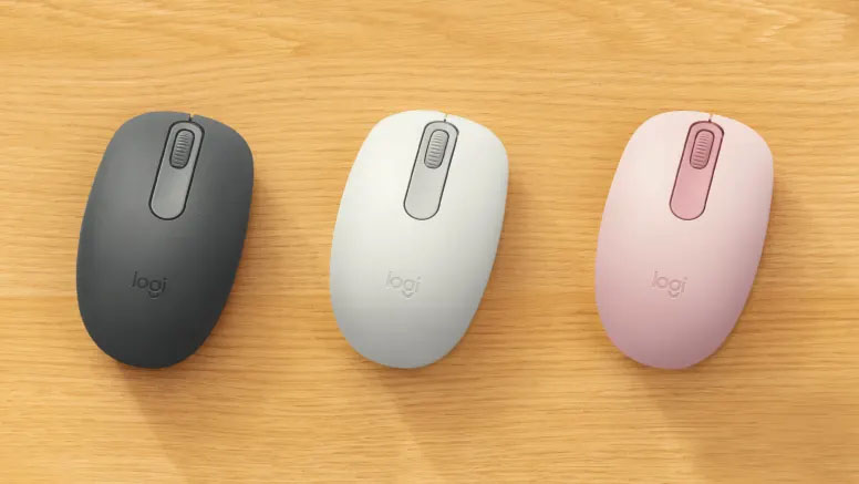 Tres mouse Logitech M196 Bluetooth en colores grafito, blanco y rosa sobre un escritorio de madera clara