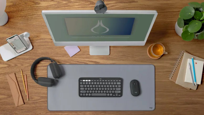 Teclado Logitech Pebble Keys 2 K380s negro y mouse a juego, vistos desde arriba en un escritorio con otros accesorios de oficina.