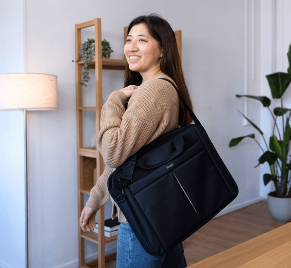 Persona transportando el bolso Trust Primo Carry negro para notebook con correa al hombro