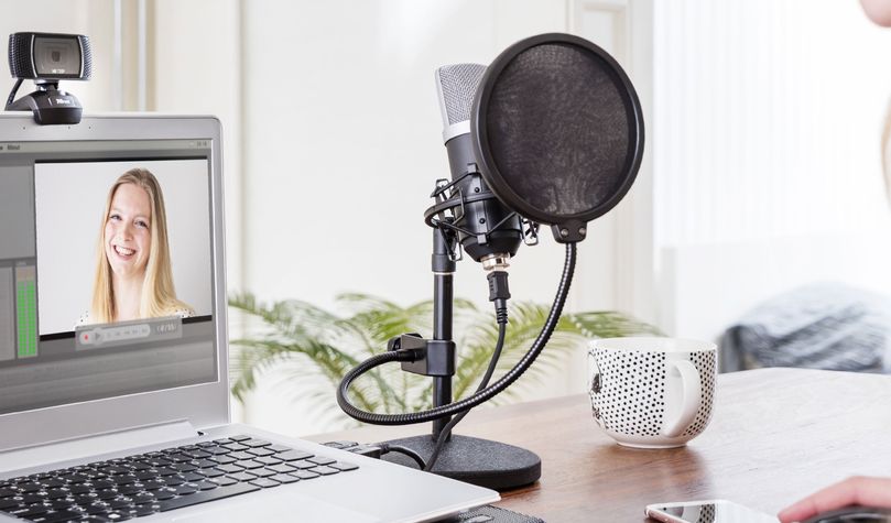 Una configuración de grabación de podcast o transmisión en vivo con un Micrófono USB para estudio Trust GXT 252 Emita frente a una laptop. En la pantalla se muestra una persona.