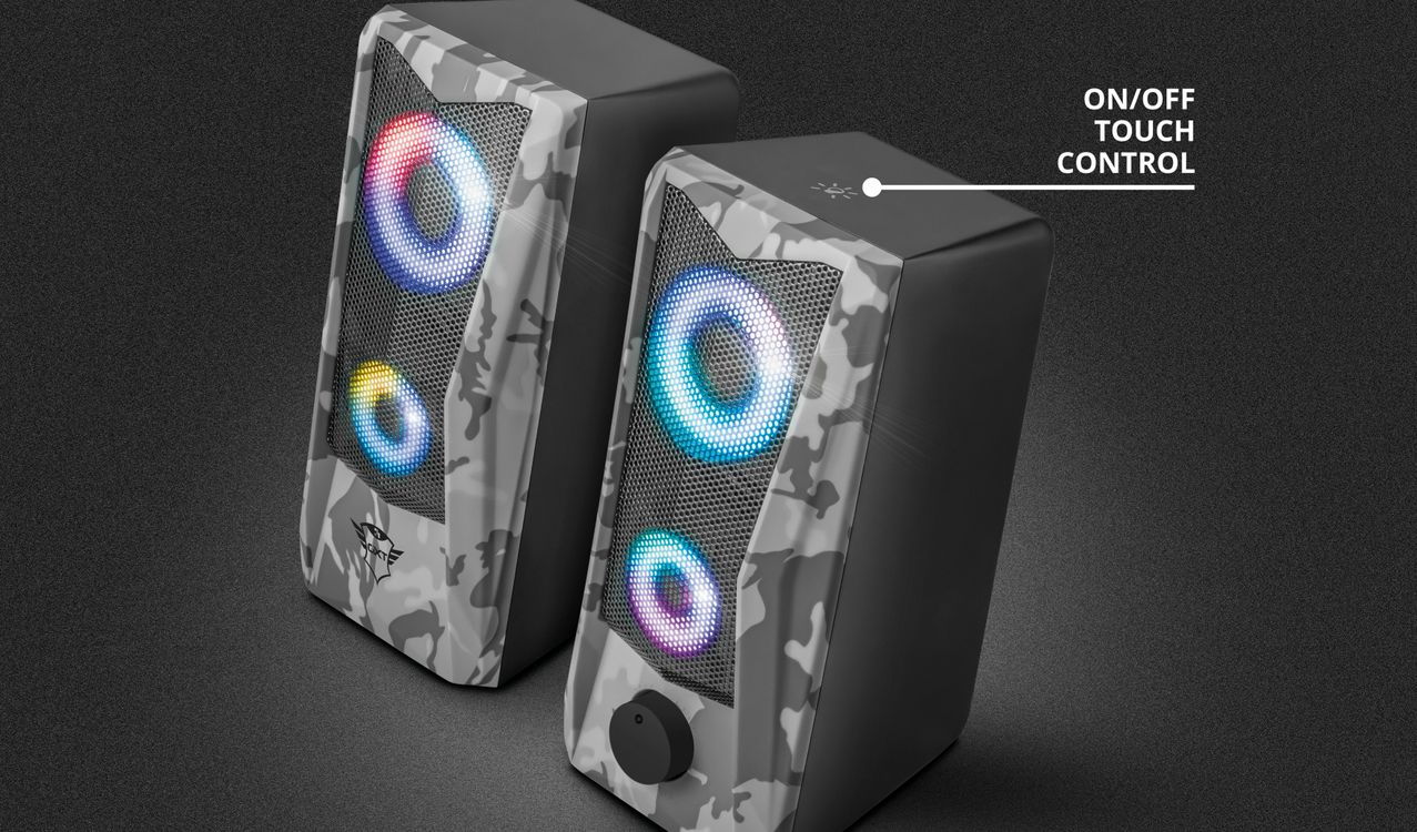 Parlantes 2.0 con iluminación RGB Trust GXT 606 Javv con diseño de camuflaje en tonos grises y negros, iluminación LED en colores azul y rojo alrededor de los woofers, control táctil de encendido/apagado indicado con texto en la parte superior derecha.