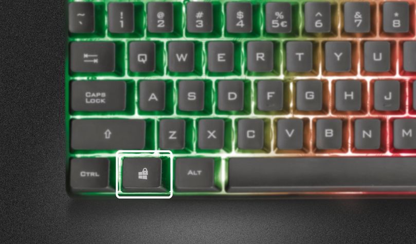 Teclado Gaming Iluminado Trust GXT 835 Azor, destacando la tecla de de modo de juego iluminada en blanco.