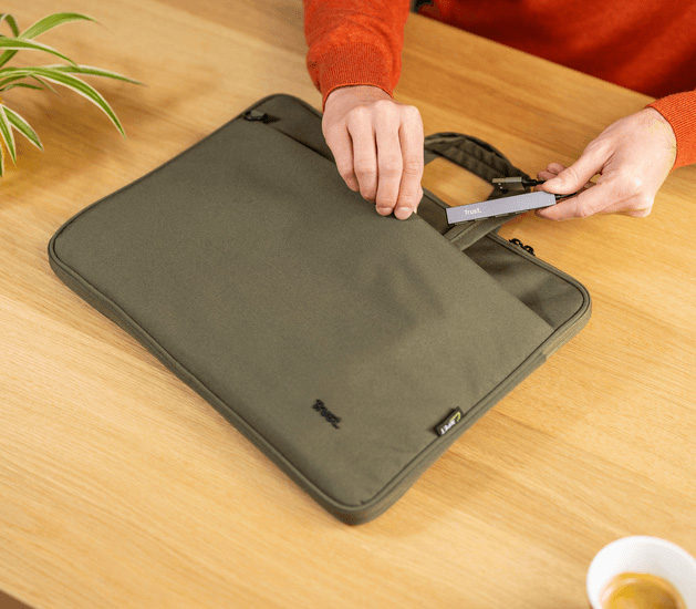 Persona guardando el hub USB mini de aluminio Trust Halyx de 4 puertos en una funda para notebook