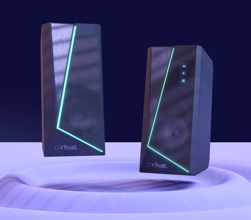 Imagen de dos Parlantes 2.0 con iluminación RGB Trust GXT 609 Zoxa, sobre una superficie reflectante y fondo oscuro.