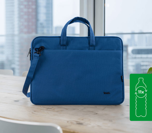 Maletín Trust Bologna Eco-friendly Slim azul para laptops de 16 pulgadas, hecho con 11 botellas recicladas, apoyado sobre una mesa de madera con un fondo de ciudad.