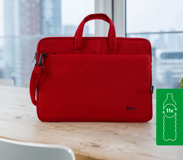 Maletín Trust Bologna Eco-friendly Slim rojo para laptops de 16 pulgadas, hecho con 11 botellas recicladas, apoyado sobre una mesa de madera con un fondo de ciudad.
