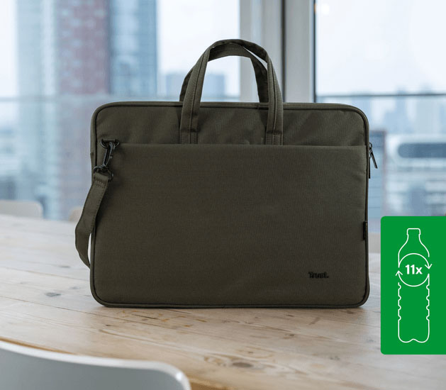 Maletín Trust Bologna Eco-friendly Slim verde para laptops de 16 pulgadas, hecho con 11 botellas recicladas, apoyado sobre una mesa de madera con un fondo de ciudad.