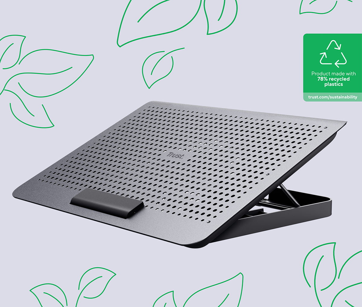 La imagen muestra Base de refrigeración para Notebook Trust Exto de color plateado con un diseño de rejilla. Se encuentra sobre un fondo gris decorado con hojas verdes estilizadas. En la esquina superior derecha, hay un texto que indica que el producto está hecho con un 78% de plásticos reciclados y proporciona un enlace a información sobre sostenibilidad.
