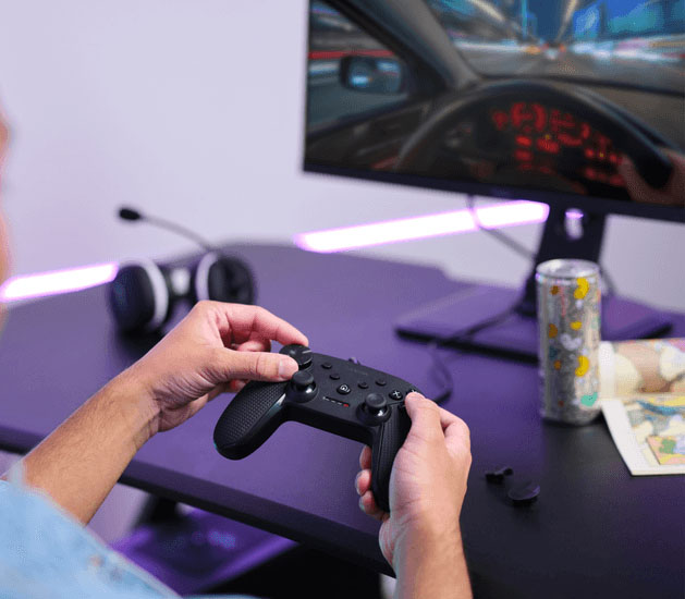 Primer plano del controlador Trust GXT 541 Muta negro en manos de un gamer, jugando en PC