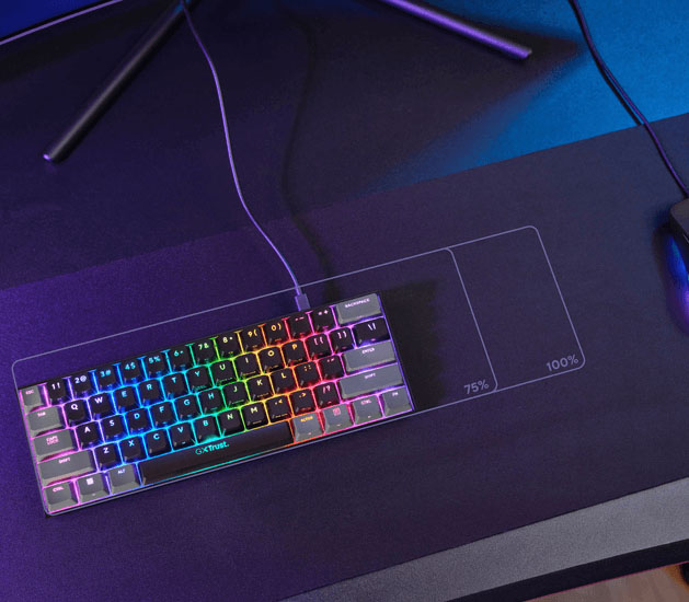 Teclado mecánico gaming mini Trust GXT 867 Acira con iluminación RGB sobre un mousepad grande con marcas de tamaño 75% y 100%