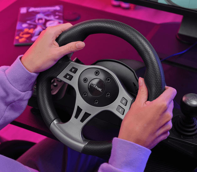 Primer plano de las manos de una chica sujetando el volante de carreras Trust GXT 289 Movi con textura perforada y botones de control visibles, en un setup de juego con luces violeta y rosa