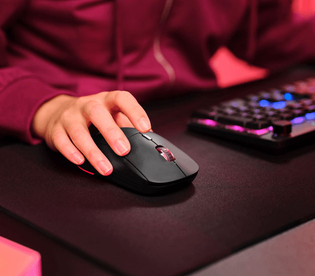 Primer plano de una mano usando el mouse inalámbrico gaming Trust GXT 926 Redex II sobre un mousepad negro