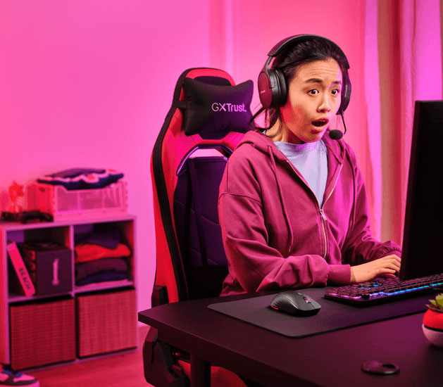 Persona usando el mouse inalámbrico gaming Trust GXT 927 Redex+ en un escritorio mientras juega con auriculares puestos