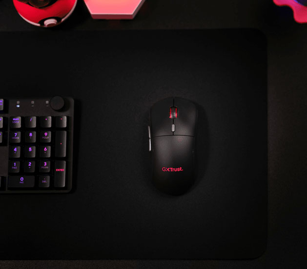 Vista superior del mouse inalámbrico gaming Trust GXT 927 Redex+ sobre un mousepad negro junto a un teclado gaming