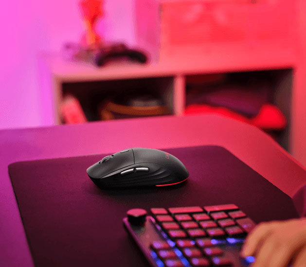 Mouse inalámbrico gaming Trust GXT 927 Redex+ sobre un mousepad negro junto a un teclado gaming iluminado
