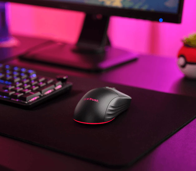 Mouse inalámbrico gaming Trust GXT 927 Redex+ con iluminación roja sobre un mousepad negro frente a un monitor