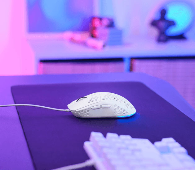 Mouse gaming Trust GXT 928W Helox ultraliviano con diseño perforado e iluminación RGB azul sobre un escritorio gamer