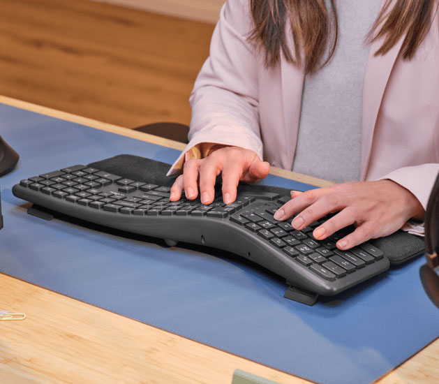 Persona escribiendo sobre el teclado inalámbrico ergonómico Trust Keyra con diseño dividido y reposamanos integrado