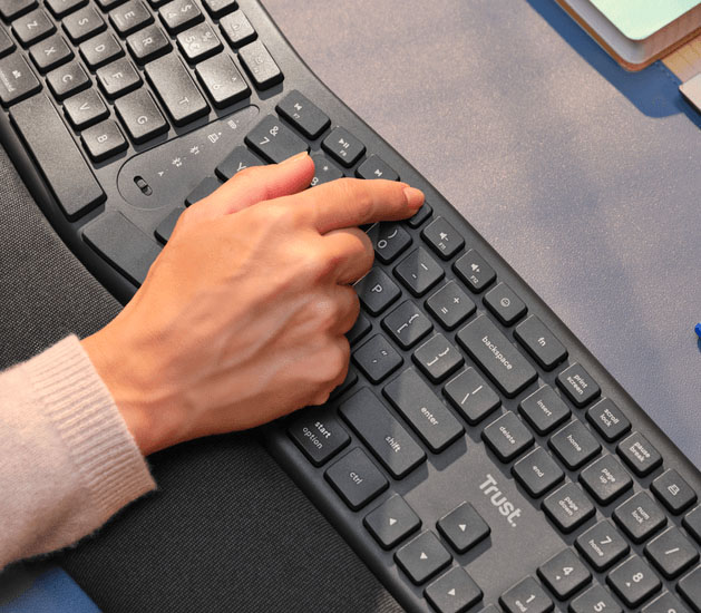 Primer plano de una mano usando una tecla de acceso rápido en el teclado inalámbrico ergonómico Trust Keyra