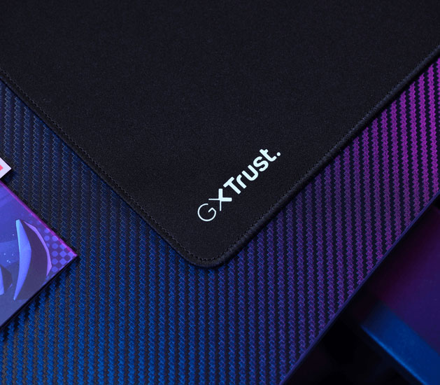 Detalle del mousepad Trust GXT con bordes cosidos y logo GXT Trust en la esquina