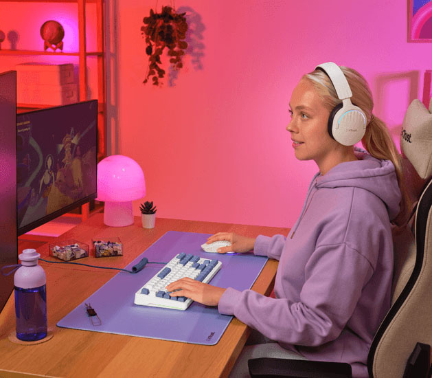 Persona usando un teclado mecánico Trust GXT 872 Xyra TKL y un mouse sobre un escritorio, con auriculares puestos frente a un monitor