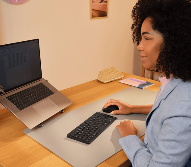 Persona usando el teclado Trust Nado II Bluetooth con notebook y mouse en un escritorio