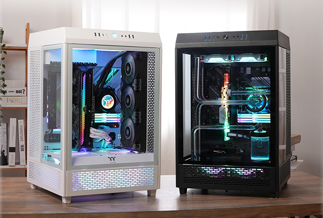 Dos Gabinetes Thermaltake The Tower 500, uno negro y uno blanco (Snow), sobre una mesa. ya armados, con componentes internos iluminados por RGB.